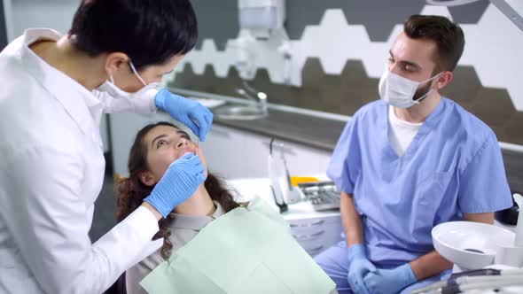 Dentist and Dental Assistant Examining Teeth of Female Patient