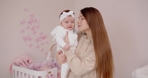 Happy Mother Holds A Newborn Baby In Her Arms And Kisses Her Tenderly