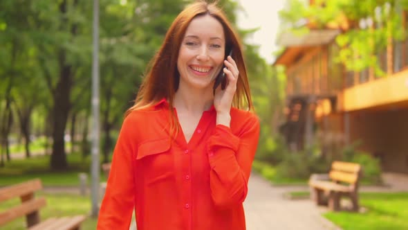 Close Up a Redheaded Businesswoman Has a Conversation By the Mobile