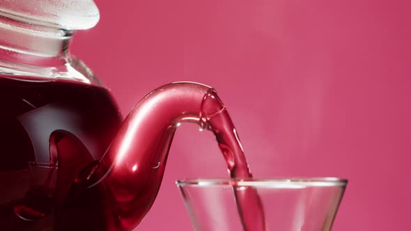 Pouring Red Fruit Tea on Pink Background
