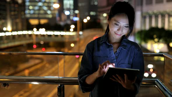 Woman looking at tablet computer at night