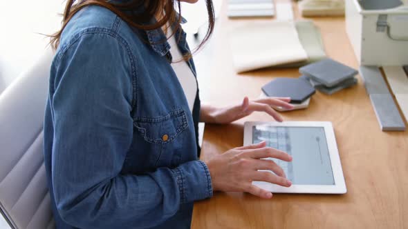 Female executive sitting at desk and using digital tablet