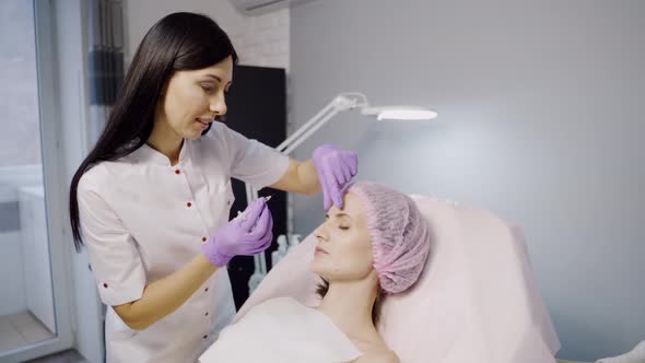 Pretty Cosmetologist with a Dark Hair Color Makes Botox for a Woman