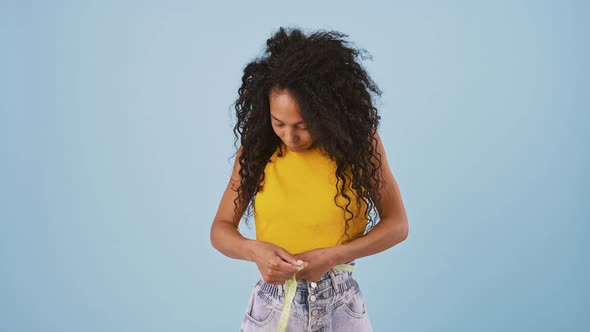 Darkskinned Lady Measures Waist with Measuring Tape