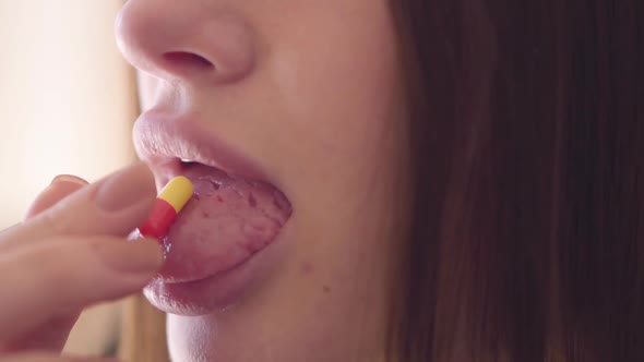 Female Hand Putting the Pill on His Tongue