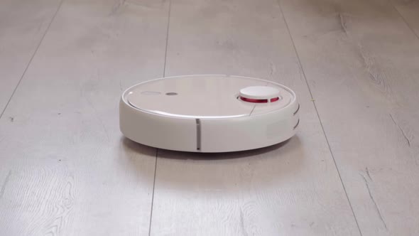 Robot vacuum cleaner vacuuming the floor in the room. Smart home with automated devices