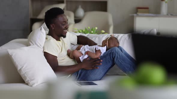 Young Father is Having Good Time with Little Baby on Couch at Apartment Room Spbi