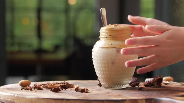 Female Hand Picking Up a Homemade Dalgona Coffee in a Mason Jar