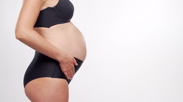 Young, happy and healthy pregnant woman in front of white background.