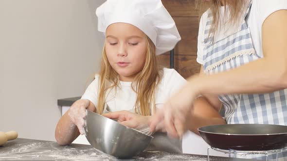 Diligent Girl with Her Daughter Kneads Dough in an Iron Bowl Want To Cook a Delicious Cake