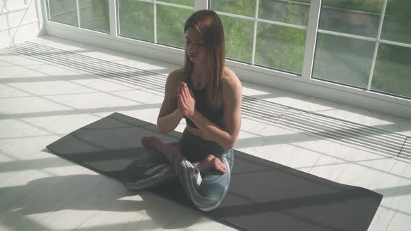 Young Female Meditates and Does Yoga a Calm Mood Relaxing in a White Room Filled with Light the Girl