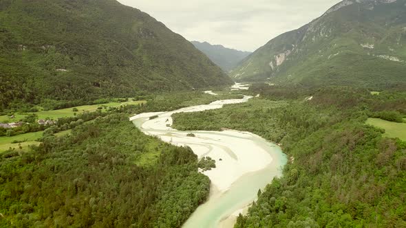 Aerial view of Soca river surrounded by a small town and many hills in Slovenia.