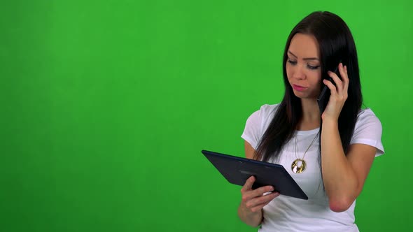 Young Pretty Woman Works on Tablet and Phone with Smartphone - Green Screen - Studio