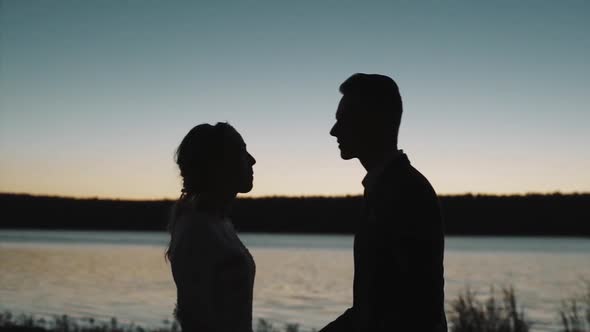 Silhouette of a couple in love at sunset in front of a river