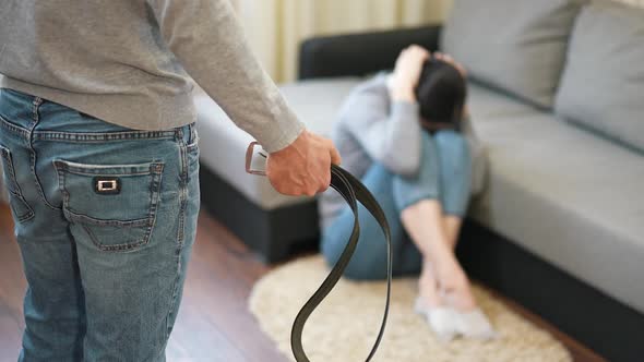 Man Man Holding a Belt in a Front of His Wife