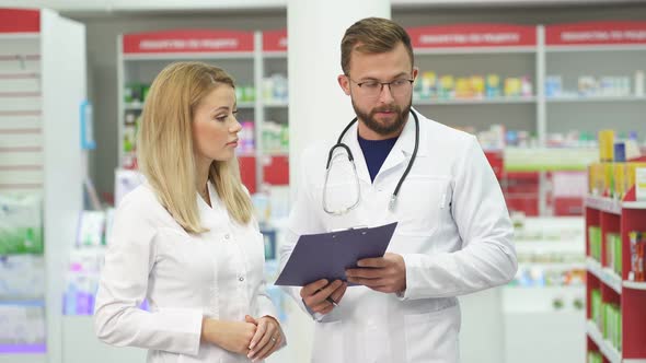 Professional Pharmacist Having Conversation with Intern in Modern Pharmacy