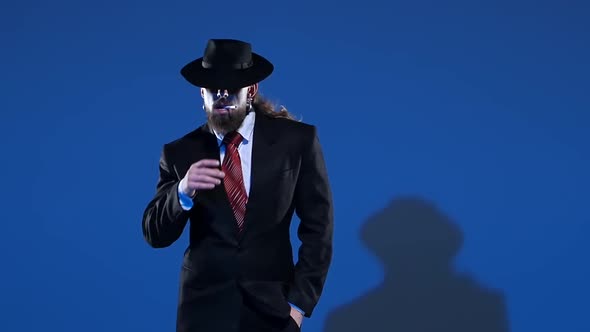 Elegant Man in a Black Hat Is Dancing an Erotic Dance. Spotlight on a Blue Background. Close Up