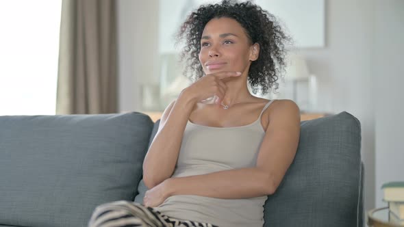 Pensive African Woman Sitting on Sofa and Thinking at Home