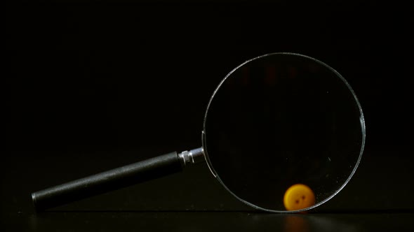 Falling buttons seen through magnifying glass, Ultra Slow Motion alt