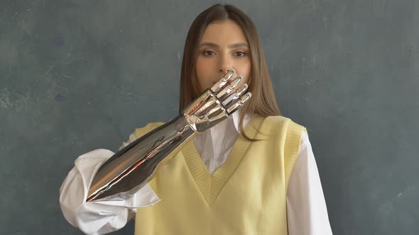 Portrait of a Beautiful Woman with a Bionic Prosthetic Arm Blows a Kiss Looks at the Camera and