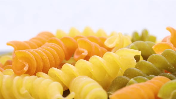 Italian colored macaroni fusilli, macro shot in 4k. Rotating motion, view from above. Close up shot.