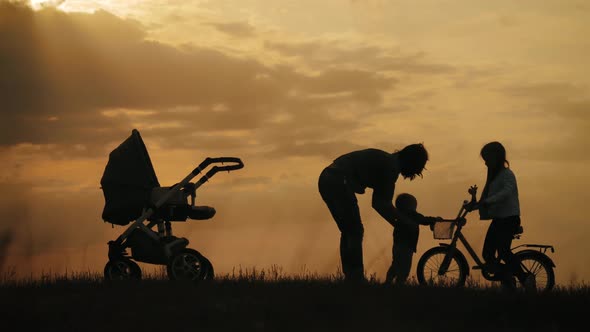 Silhouettes of Happy Mother Having Good Time with Their Little Children on Park