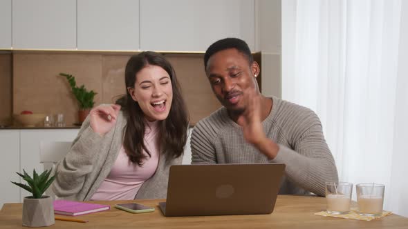 Young Adult Couple Having an Online Conference Video Call with Their Friends at Apartment Kitchen