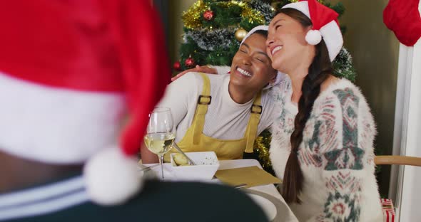 Two diverse female friends celebrating meal with friends at christmas time