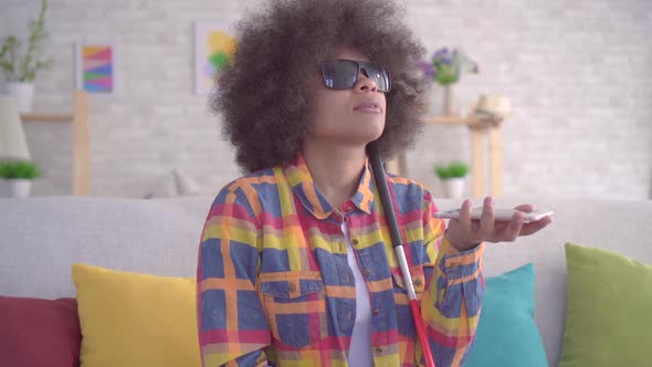 African American Woman with an Afro Hairstyle Visually Impaired Uses Voice Assistant