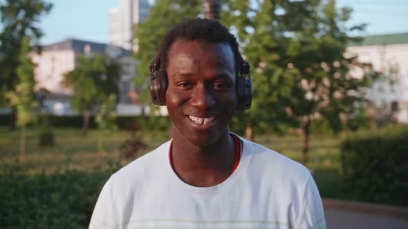 A Young Black Student with Headphones Walks Through the City Centre at Sunset