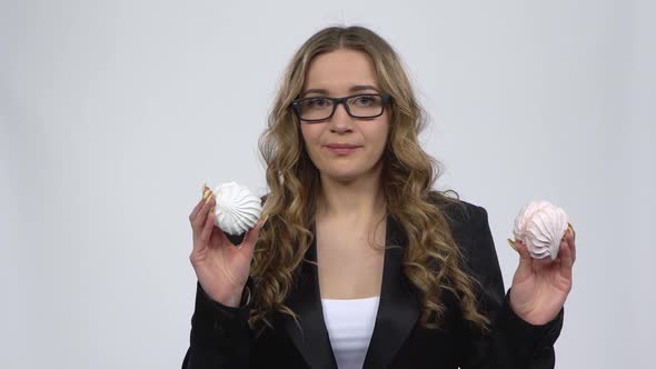 Beautiful Woman Eagerly Eating Sweet White Marshmallow, Isolated on a Gray Background.