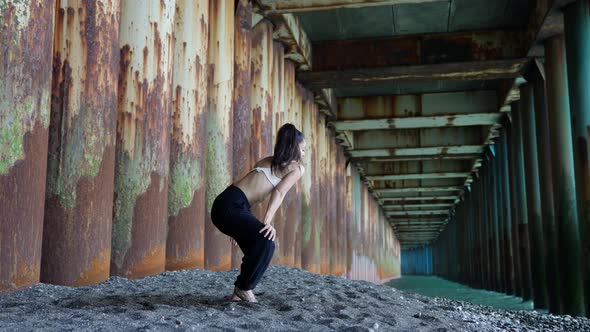 Female Dance Performer is Rehearsing Alone on Coast of Sea Dancing Under Pier