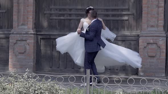 Handsome Fiance Holds and Spins Bride in Long White Dress