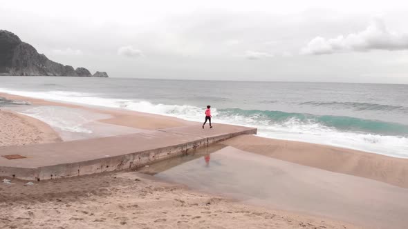 Woman raises hand on edge of sea, celebrating achievement