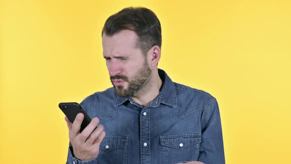 Beard Young Man Talking Getting Angry on Smartphone, Yellow Background