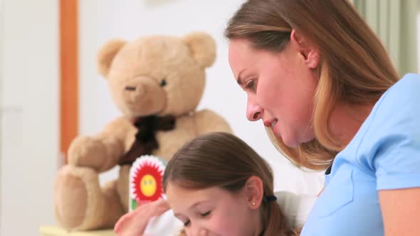 Mother with her daughter in a hospital ward looking at a card