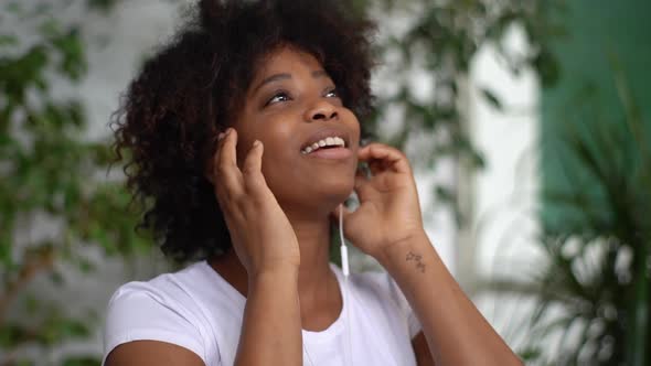 Closeup Face of Cheerful African Young Woman Putting on Headphones and Starting to Listen Favorite