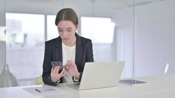 Attractive Young Businesswoman Using Smartphone in Office