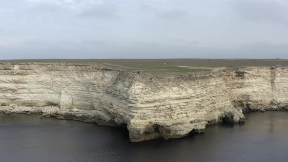 White Steep Rocky Cliff with Meadows and People Silhouettes