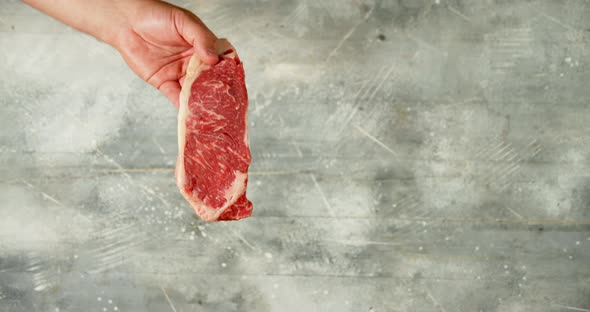 Raw Steak Beef Striploin Holds a Man's Hand. 