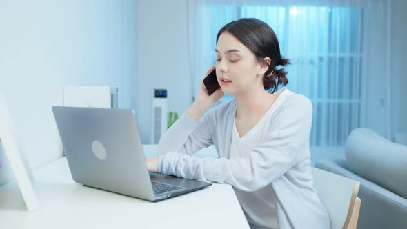 Asian young beautiful businesswoman use mobile phone call working at home during night time