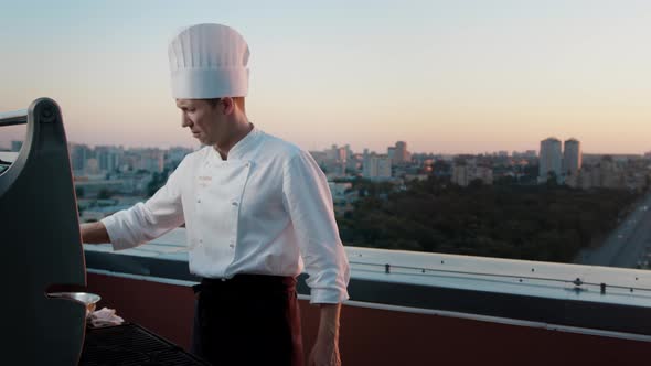 A professional Chef prepares a barbecue on the roof of a skyscraper. An expensive restaurant
