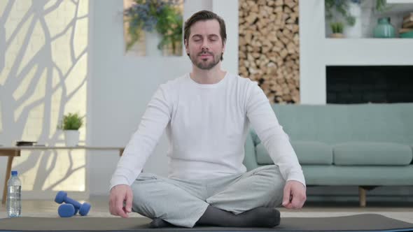 Portrait of Young Man Doing Yoga on Yoga Mat at Home