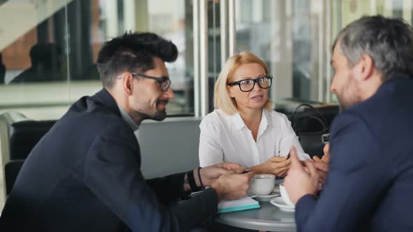 Cheerful Coworkers Socializing in Cafe Talking and Smiling Enjoying Coffee Break