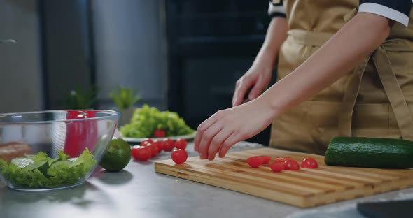 Woman Holding a Knife in Her Hands and Cutting Tomatoes while Cooking Vegetable Salad