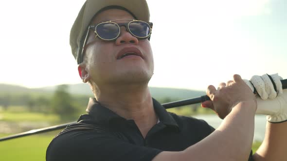 4K Portrait of Asian man golfer golfing on golf course at country club at summer sunny day.