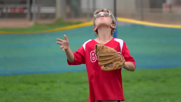 A boy practices playing catch on a little league baseball field.