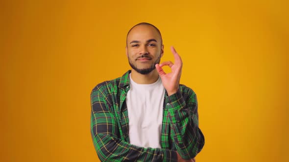 Positive Young African American Guy Showing OK Sign Against Yellow Background