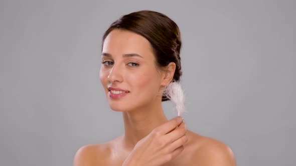 Beautiful Woman with Feather Touching Her Face