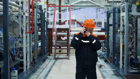 A Bearded Man in a Helmet Stands at His Workplace Checking the Operation of the Radio for